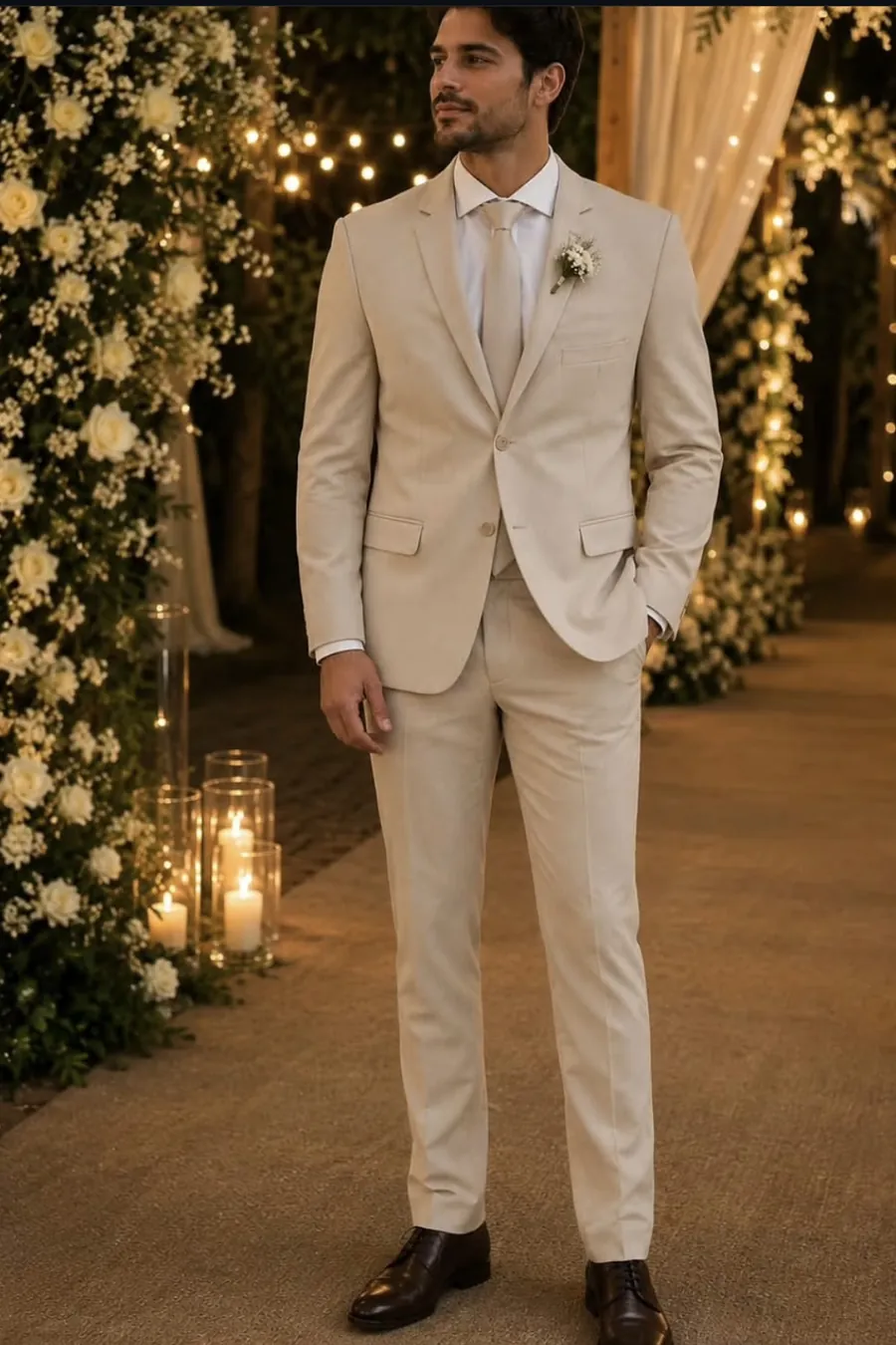 Terno de noivo bege claro com gravata e flor na lapela, em casamento ao ar livre